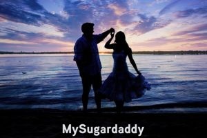 Criterios para elegir un Sugar Daddy: Momento azucarado Criterios para elegir un Sugar Daddy: En la imagen vemos un momento inolvidable entre una Sugar Baby y un Sugar Daddy. Disfrutan de un atardecer a las orillas del mar. El cielo esta hermoso, ya que la luz se refleja en diferentes colores