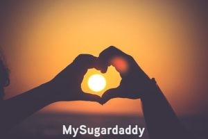 Cómo llegar a un acuerdo con un Sugar Daddy: Relación amorosa Cómo llegar a un acuerdo con un Sugar Daddy: En la imagen vemos dos manos, de dos personas distintas, haciendo el símbolo del corazón. En el fondo esta un atardecer hermoso y espectacular. Por seguro, estas dos personas se entienden bien y tienen una relación apasionada.